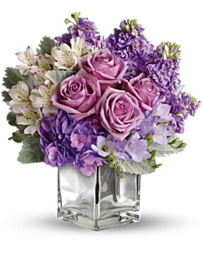 <p>Visions of sugar plum fairies dance to life with this magical bouquet. Lush lavenders, frosty whites and silvery greens look romantic and refreshing inside a cool cube vase.<br />
Robust roses, delicate hydrangea and feminine stock make a cool collection inside an icy, clear glass cube vase.</p>