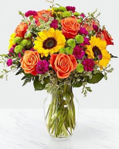 The Color Craze Bouquet blooms with a vibrant energy to create a special moment for your recipient! Our floral professionals weave together a blend of orange roses, sunflowers, violet mini carnations, green button poms, and lush greens to create an incredible gift. Presented in a clear glass vase, this truly colorful display of fresh flowers is ready to send your warmest birthday, thank you, or get well wishes straight to their door.

STANDARD bouquet is approx. 15H x 12W.
DELUXE bouquet is approx. 15H x 13W.
PREMIUM bouquet is approx. 16H x 14W.