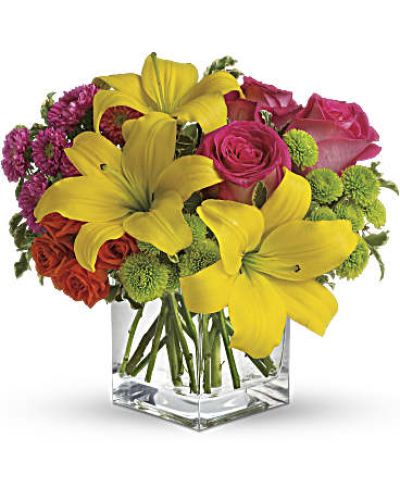 Splash into spring! Sun-bright yellow, hot pink and orange blooms add up to a sensational and oh-so-stylish spring & summer floral arrangement for any occasion.
Hot pink and orange roses are mixed with yellow asiatic lilies, hot pink matsumoto asters and lime green button spray chrysanthemums in a clear glass cube vase.