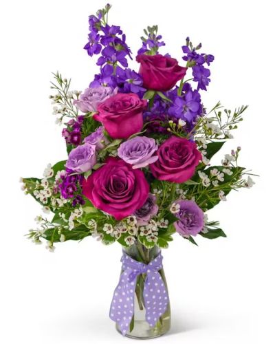 There is just something majestic about A Queen's Beauty. Just like a true queen, this bouquet blends both grace and strength in its royal hues of purple. Just above a purple ribbon, blooms abound. Richly colored roses, sweet William, and waxflower.